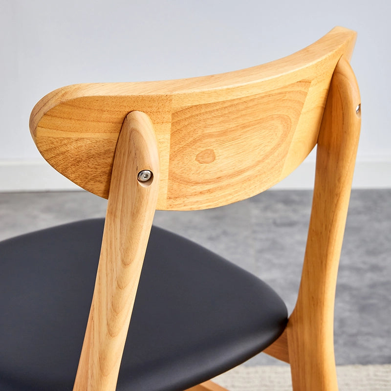 Elegant set of 4 upholstered dining chairs with curved backrest in a dining room setting.