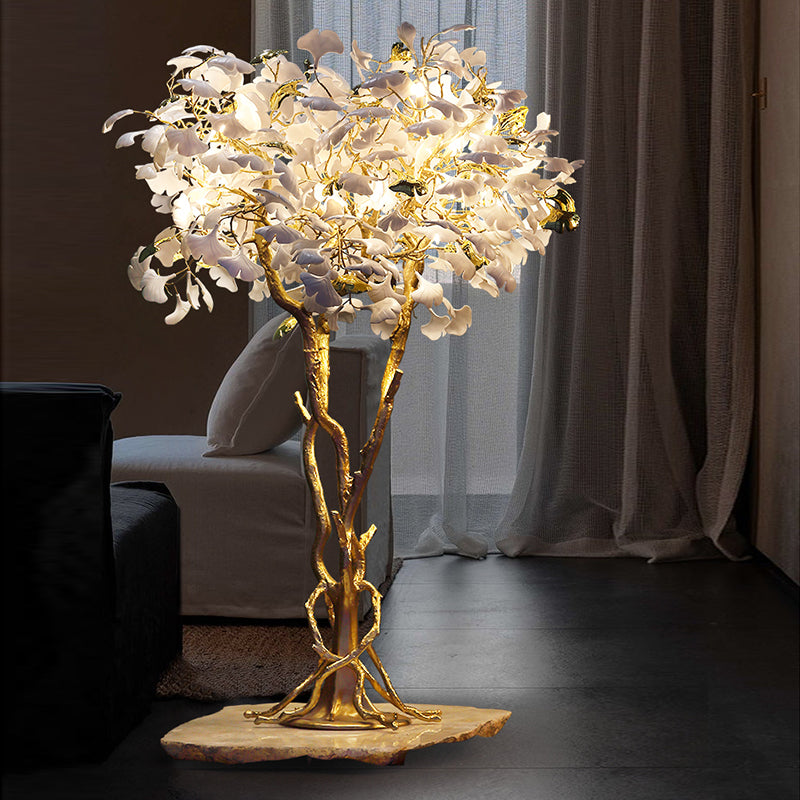 Ginkgo tree floor lamp glowing warmly in a stylish living room corner.