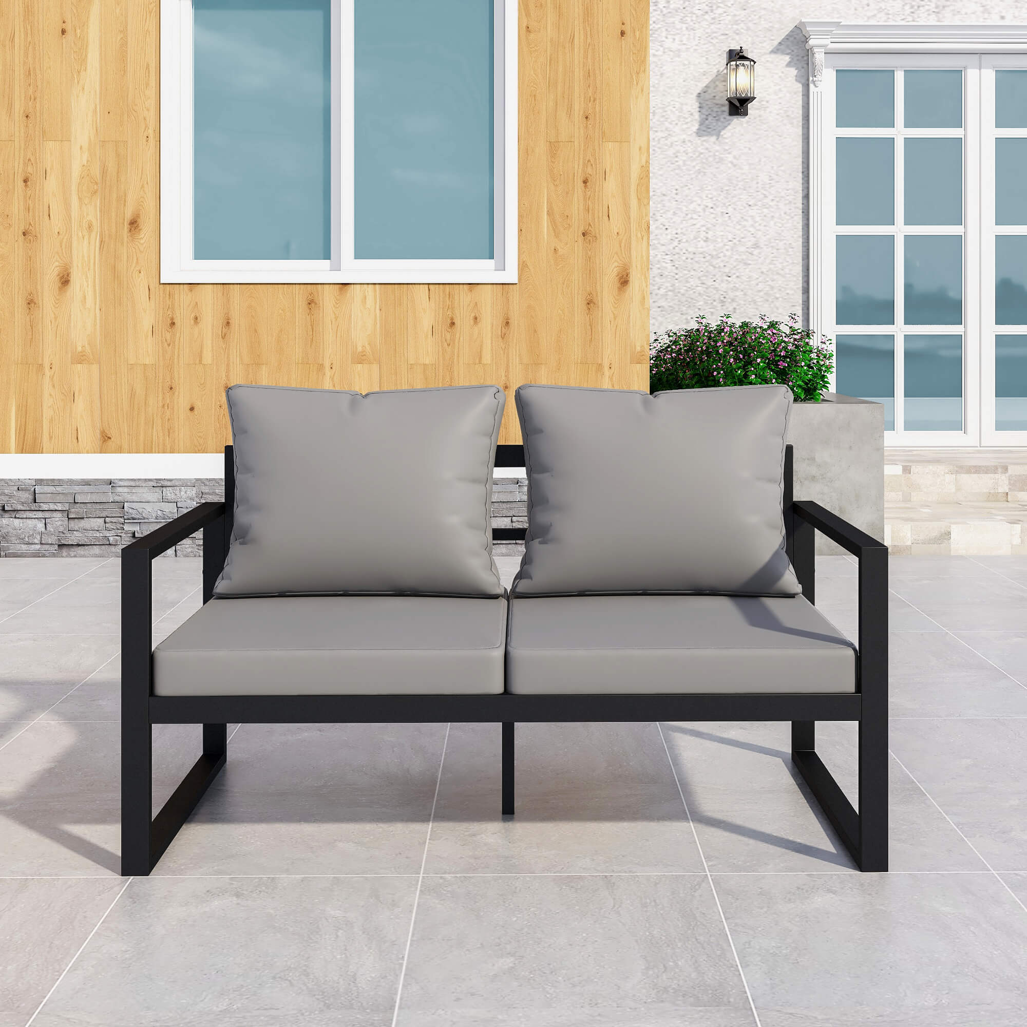 Grey outdoor loveseat with plush cushions in a garden setting