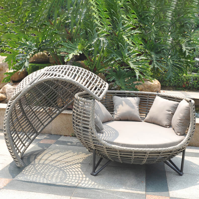 The Nordic rattan daybed in a sunny garden setting, highlighting its stylish shape and durability.