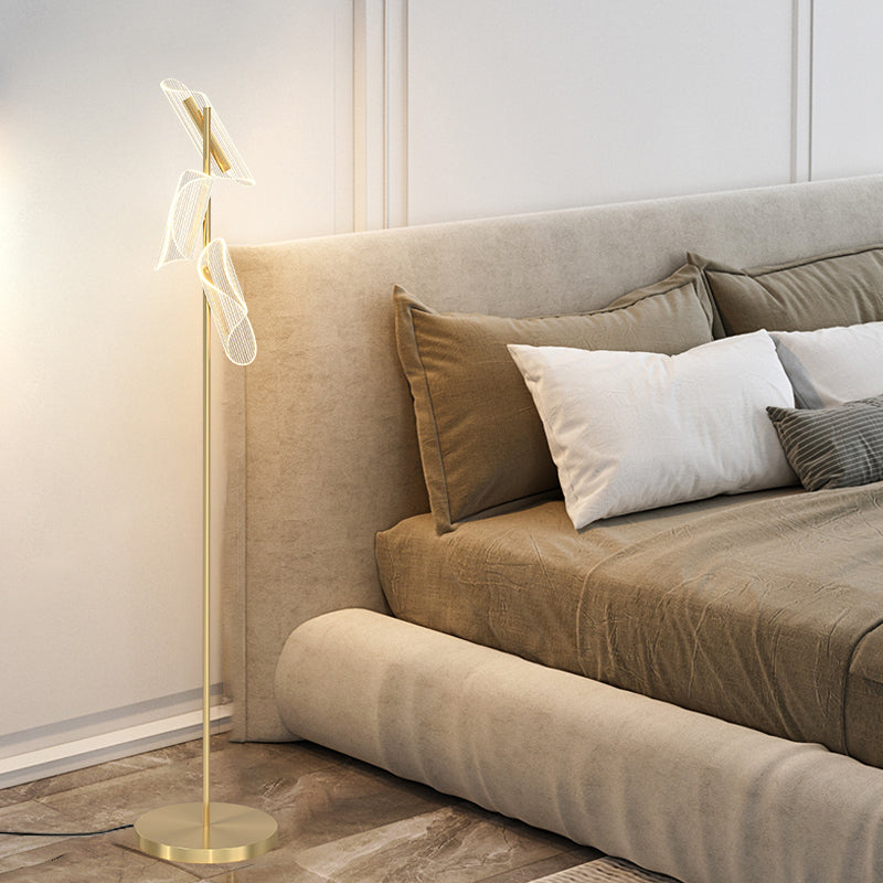 Modern brass stand LED floor lamp in a cozy reading nook, providing ambient light.