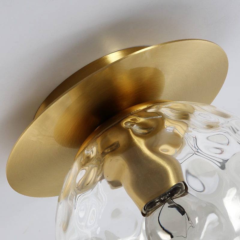 Close-up view of the mouth-blown glass sphere in the elegant gold ceiling light, highlighting its exquisite craftsmanship.