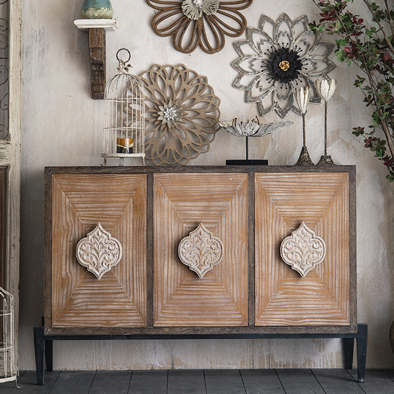 Close-up view of the rustic cabinet's intricate carvings and distressed finish.