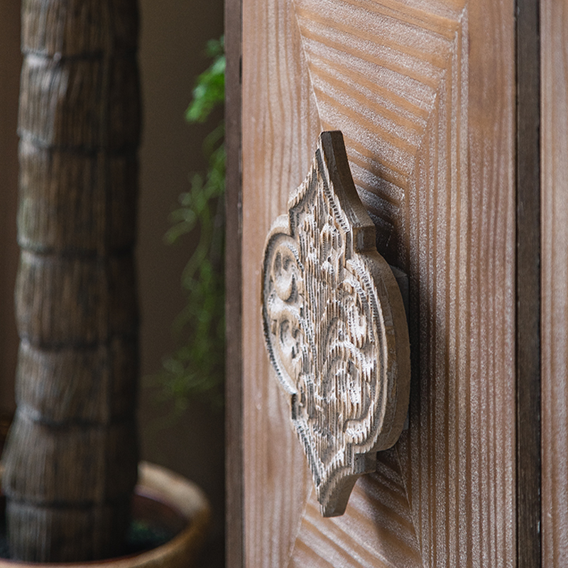 Close-up view of the rustic cabinets intricate carvings and distressed finish.