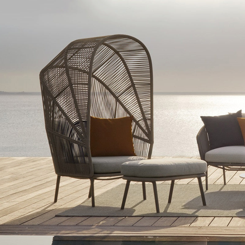 Luxury handwoven cocoon chair with a footstool in a garden setting.