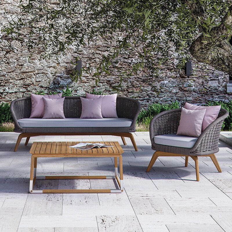 Close-up of the Elegance Rattan and Teakwood Patio Set highlighting the plush cushions and handwoven design.