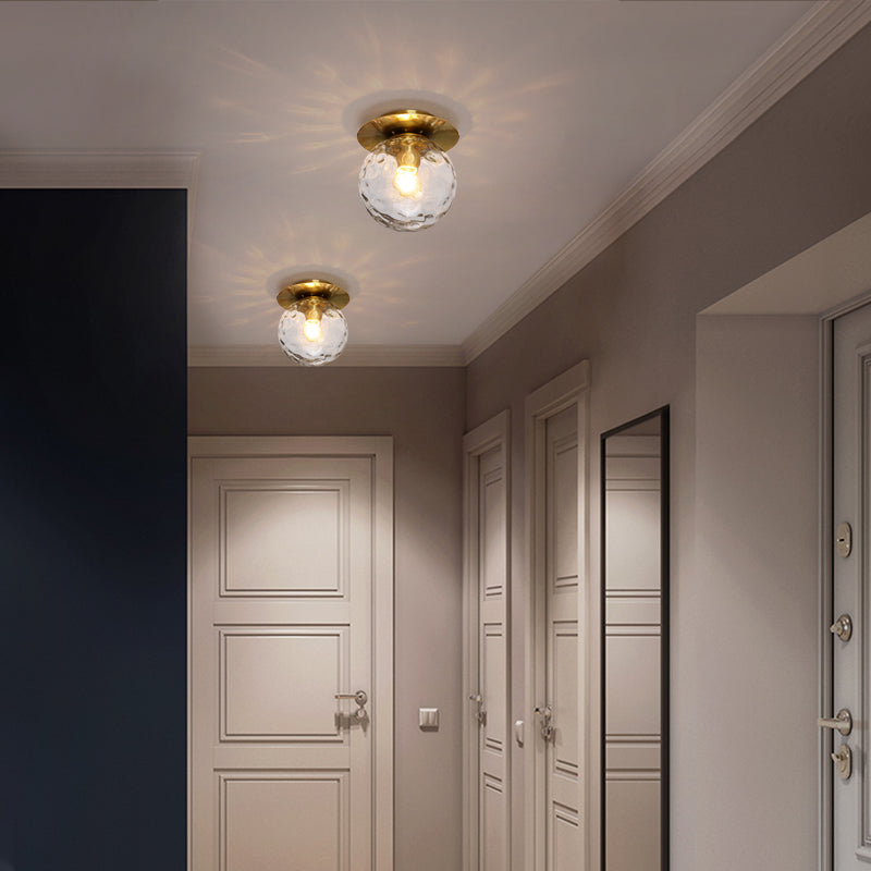 Close-up view of the mouth-blown glass sphere in the elegant gold ceiling light, highlighting its exquisite craftsmanship.