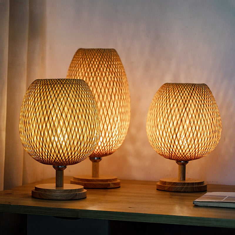Front view of handwoven bamboo lamp with wooden base in a cozy bedroom setting.