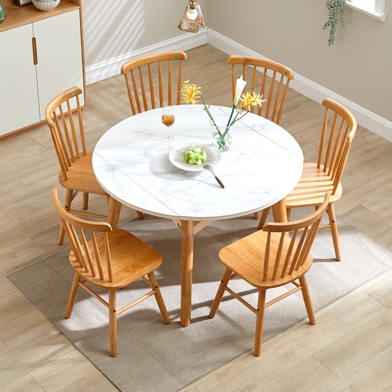 View of the modern round extendable dining table with light brown legs in a cozy dining room setting.