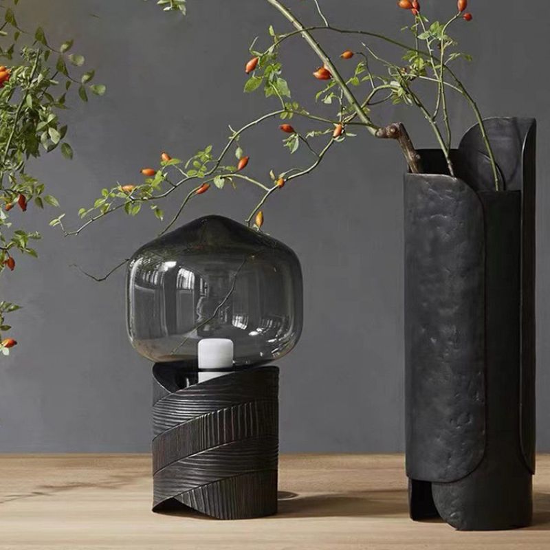 Modern bronze lamp placed on a bedside table with a grey shade.