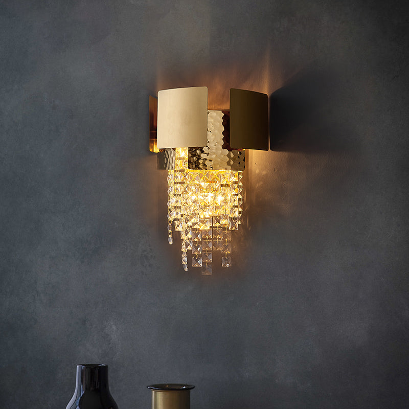 Elegant gold crystal raindrop wall sconce illuminating a modern dining area with a luxurious touch.