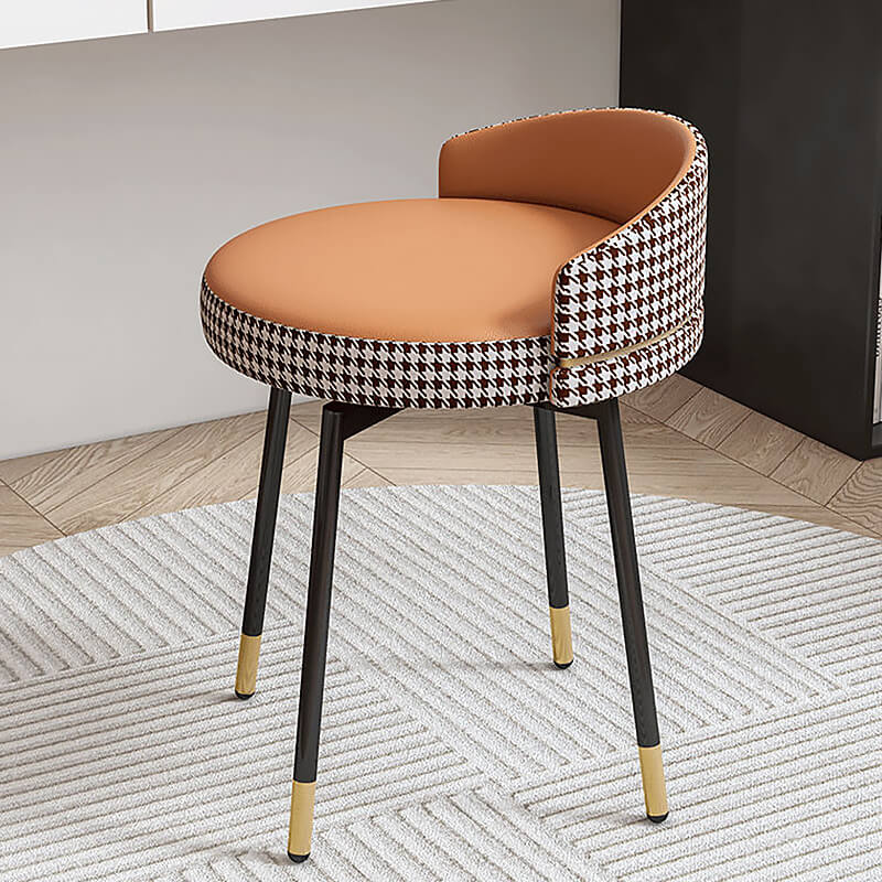 Side view of the houndstooth dressing stool styled next to a vanity table in a small bedroom