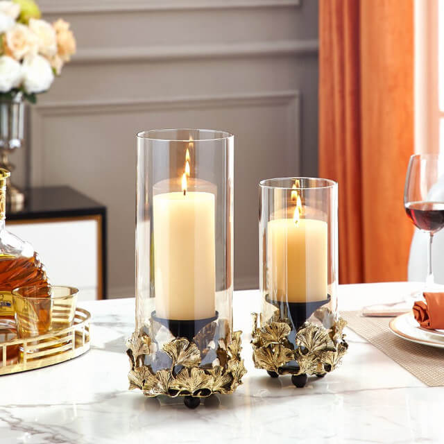 Elegant gold hurricane glass candle holder set displayed on a dining table.