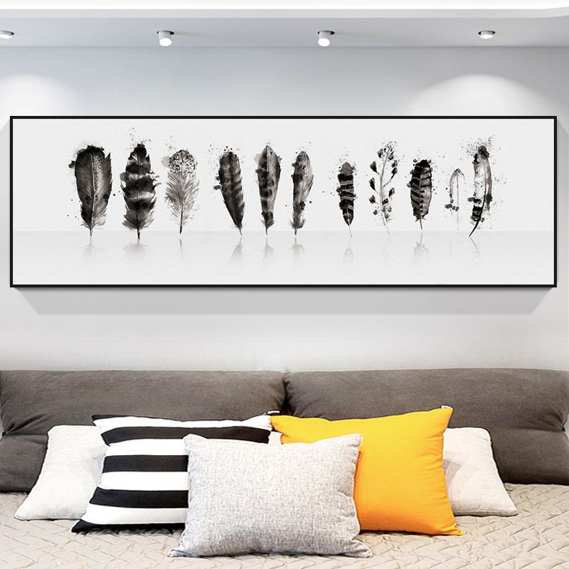 Angled view of black and white feather wall art hanging in a modern living room
