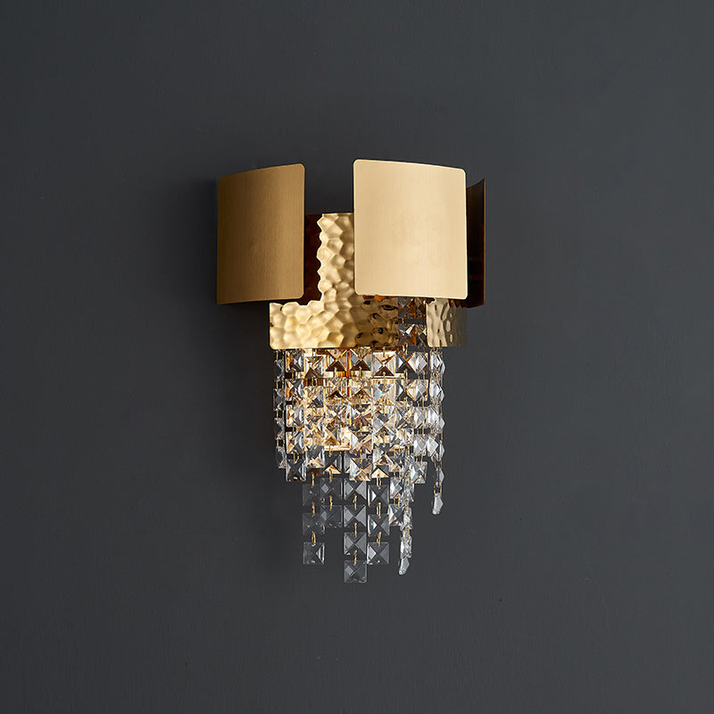 Elegant gold crystal raindrop wall sconce installed in a stylish bedroom setting, providing warm light.
