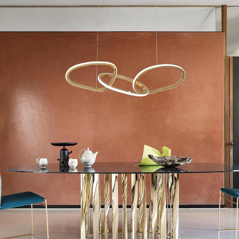 Geometric gold ring LED pendant light hanging over a dining table.
